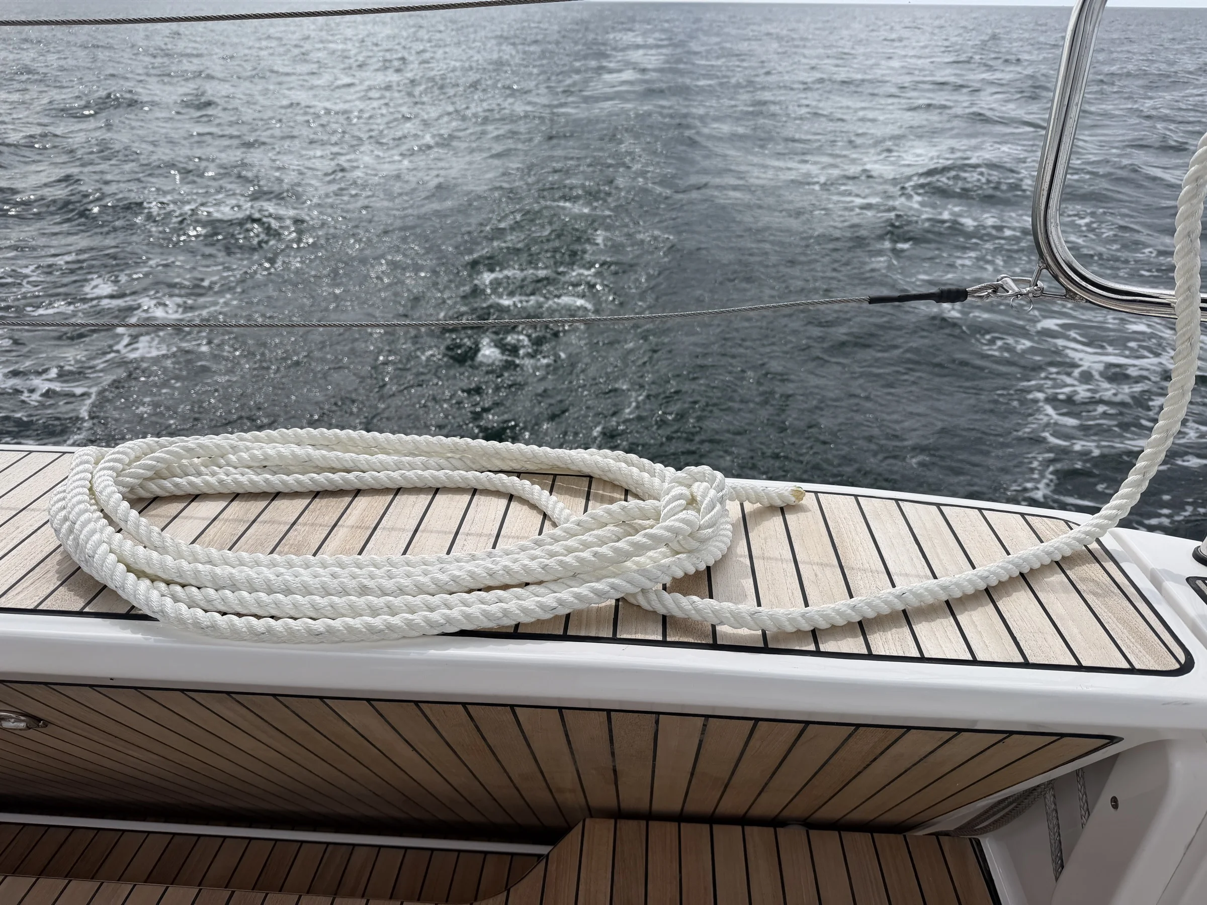 Festgemachte Leine auf dem Teakdeck – Ostsee im Hintergrund